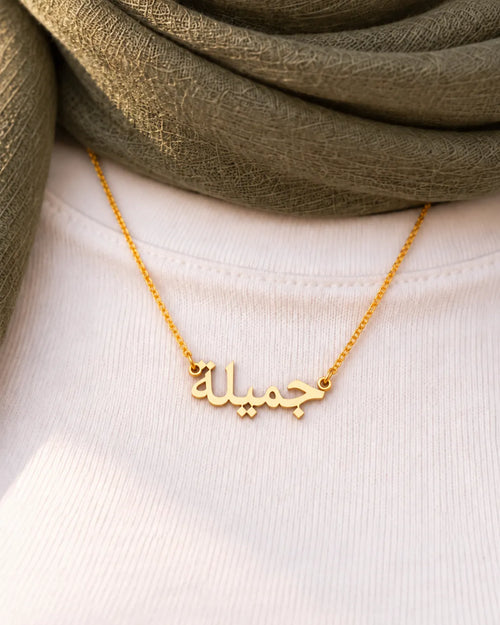 Goldene arabische Jamila-Namenskette (جميلة), Nahaufnahme auf weißem Oberteil und olivfarbenem Kopftuch